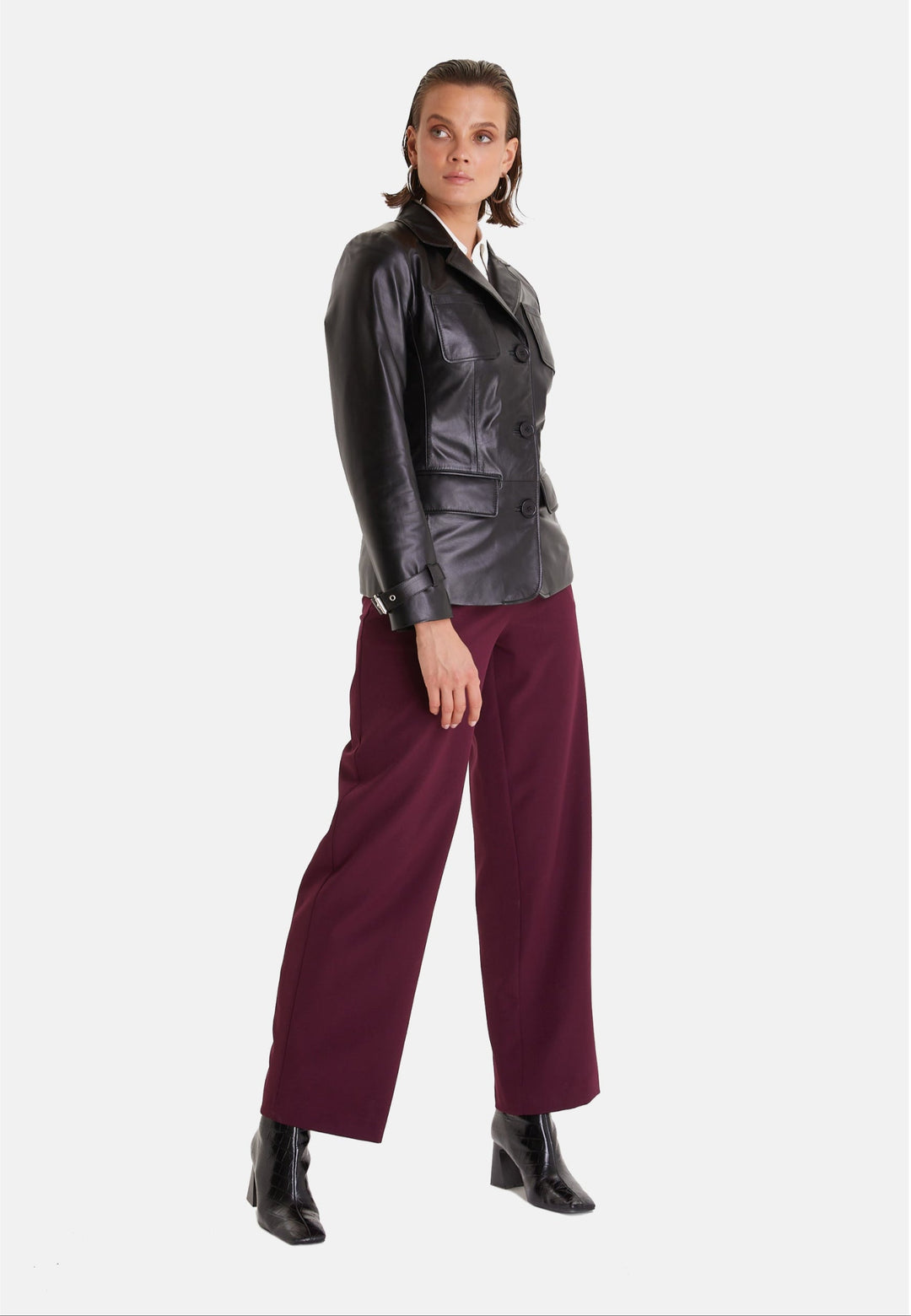 Woman wearing black leather jacket and burgundy trousers