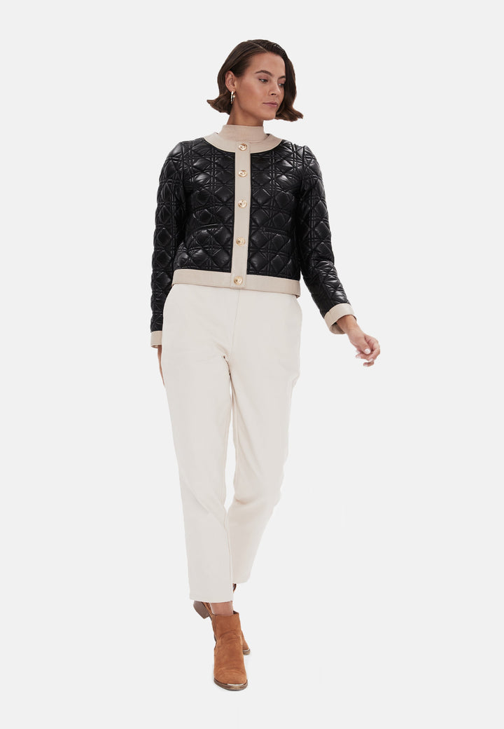 Woman wearing black quilted jacket and cream trousers