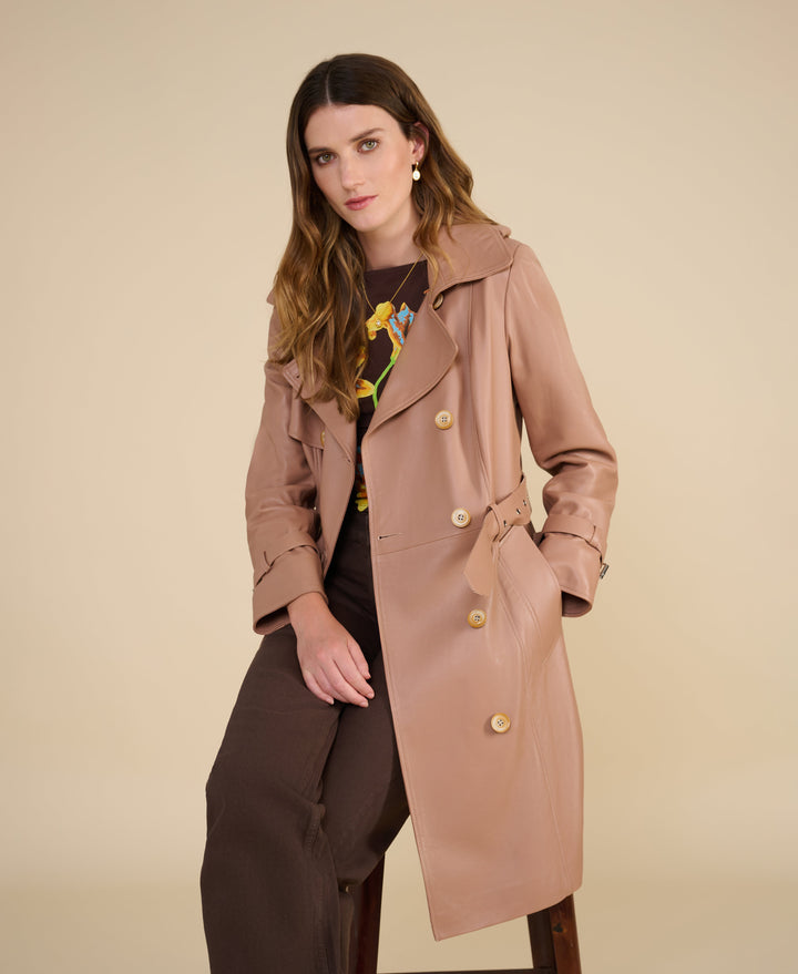 Woman in tan trench coat seated