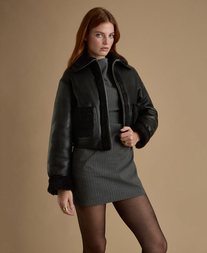 Woman wearing black shearling cropped jacket
