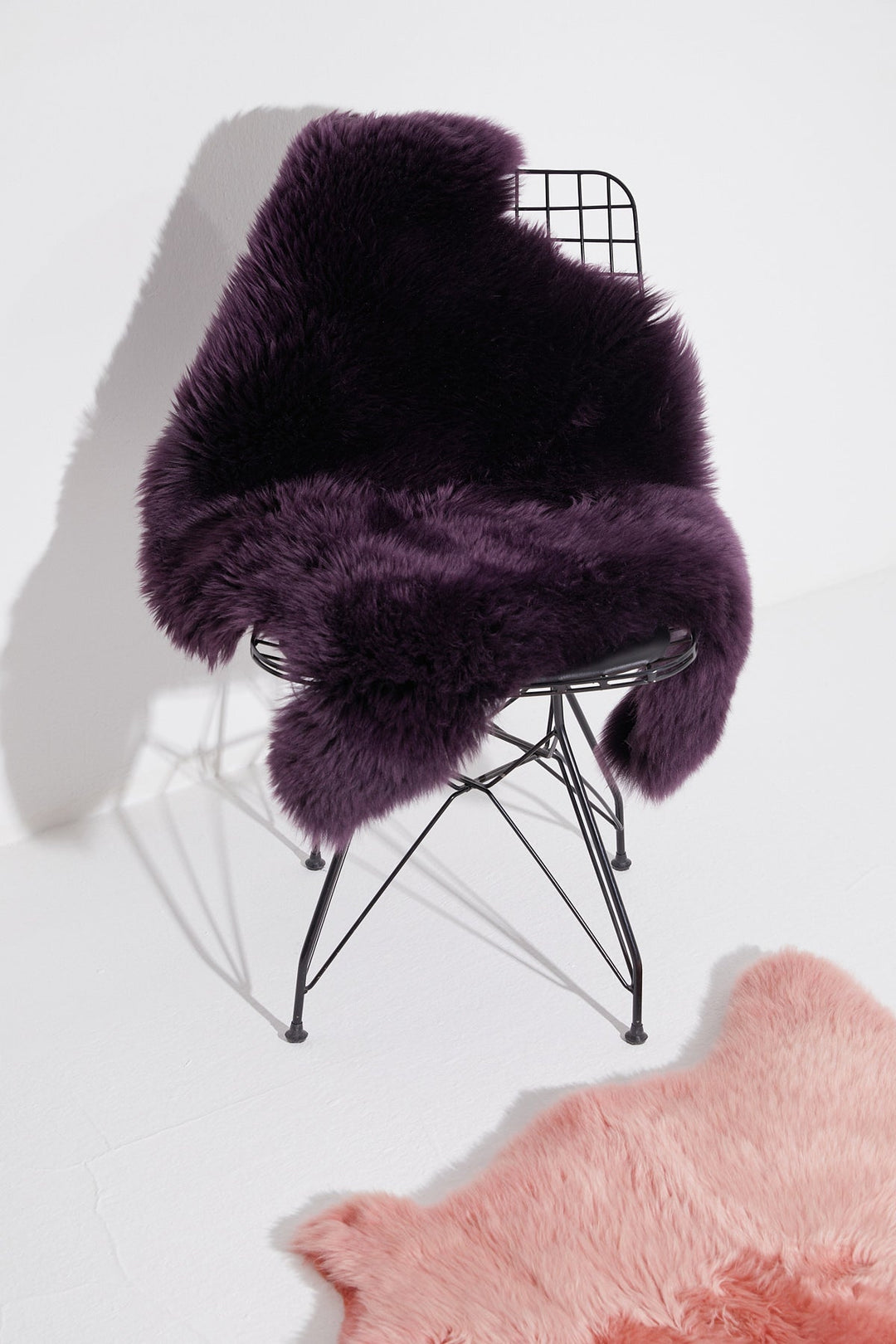 Dark purple sheepskin rug on wire chair