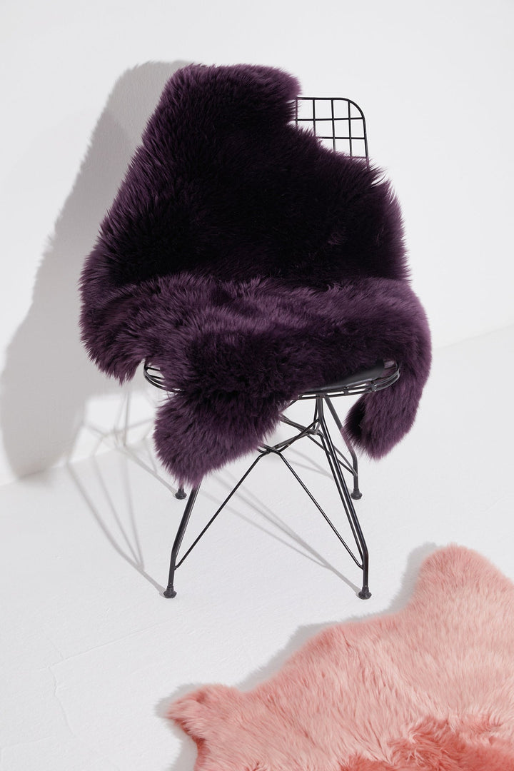 Dark purple sheepskin rug on wire chair