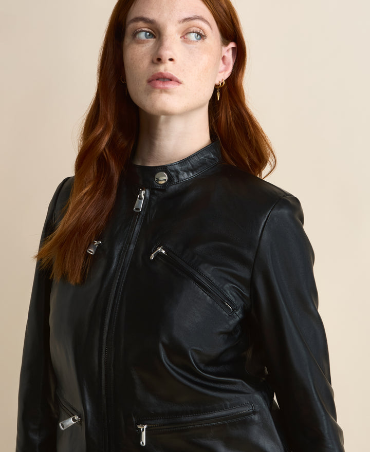 Close-up of black leather jacket with silver zip detailing and high neck collar on model