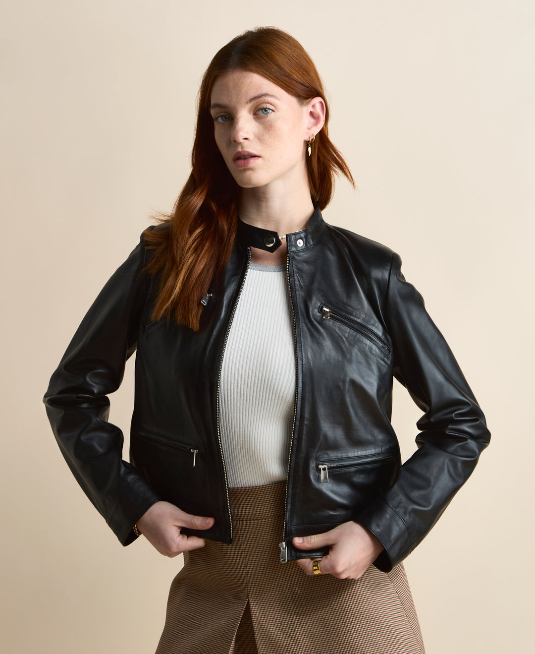 Black leather jacket worn open over white ribbed top and brown skirt, front styling detail