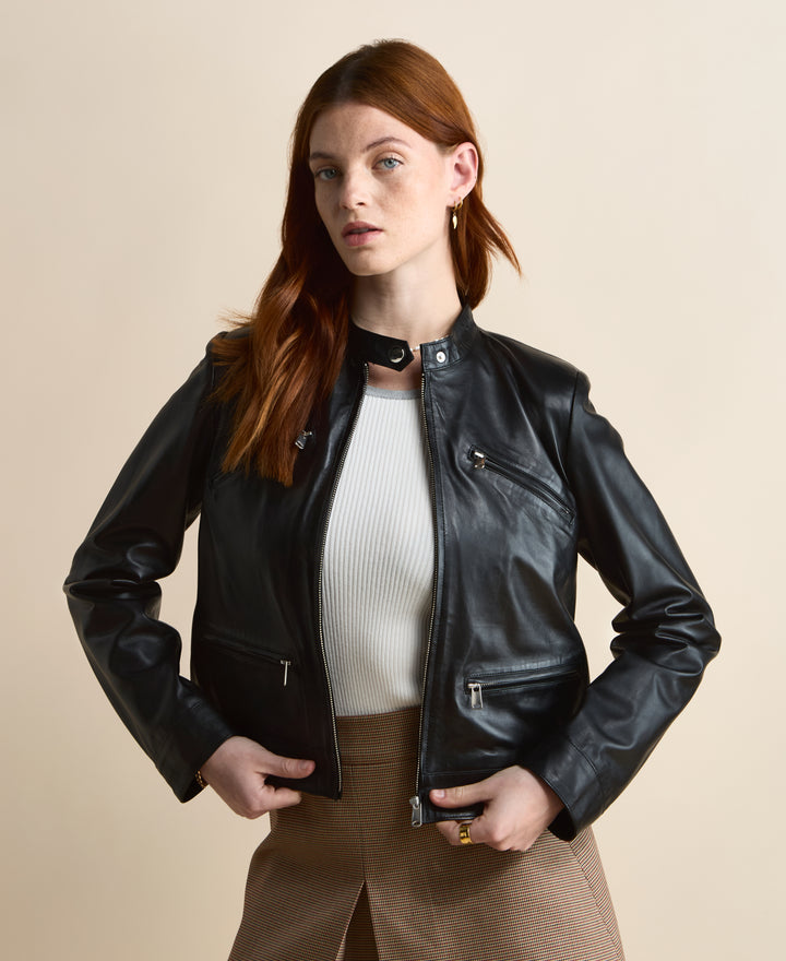 Black leather jacket worn open over white ribbed top and brown skirt, front styling detail