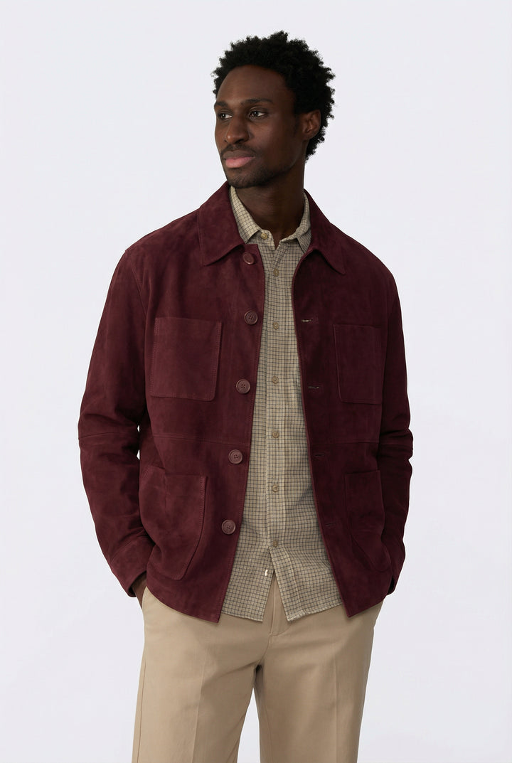 Man wearing a burgundy jacket over a patterned shirt on a white background