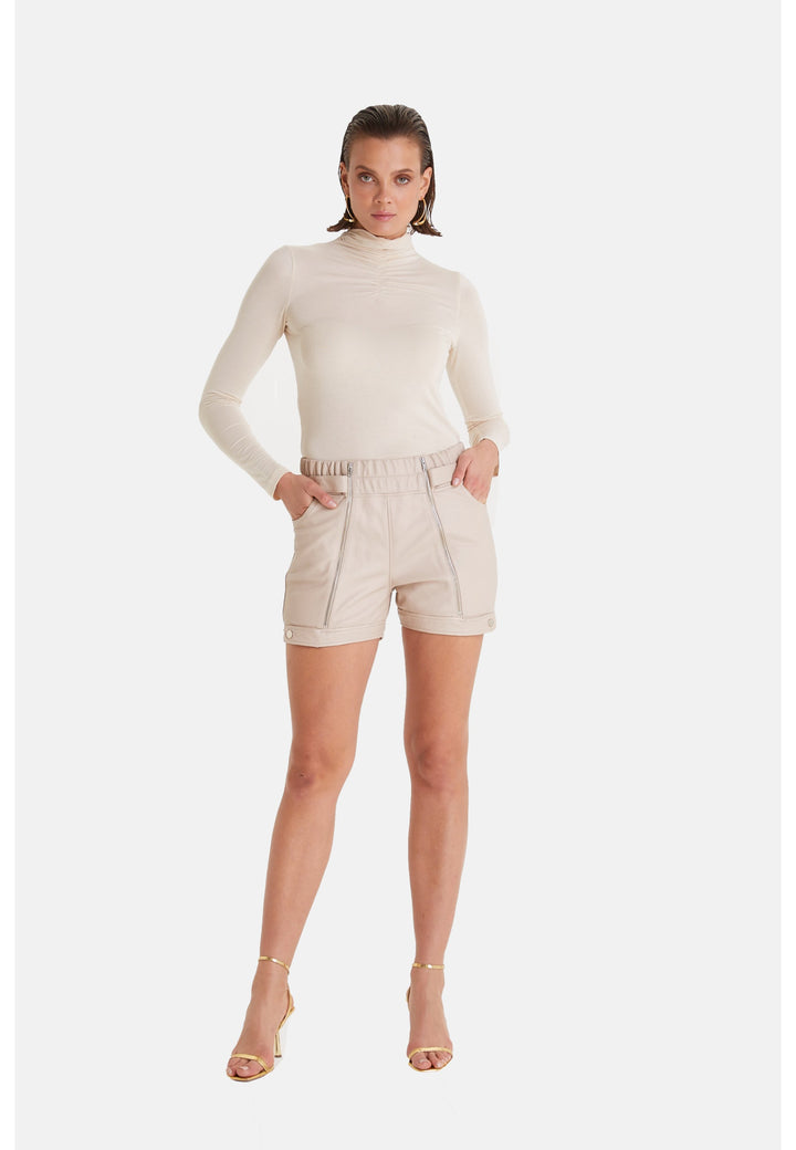 Woman wearing beige leather shorts and turtleneck