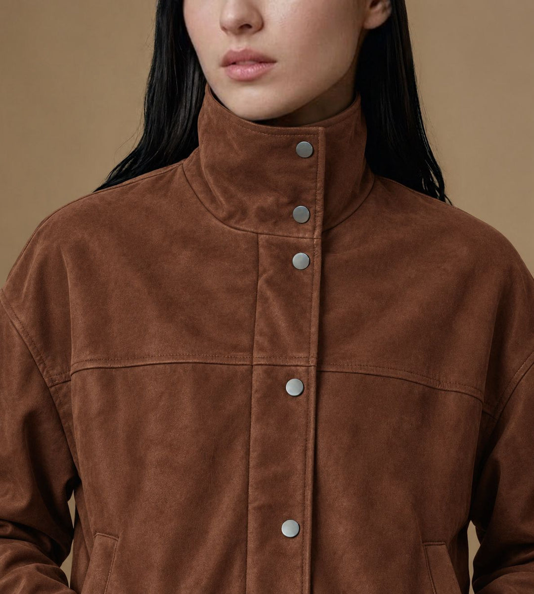 Close-up of the Arden jacket’s chestnut brown suede texture, funnel collar and metal snap fastenings.