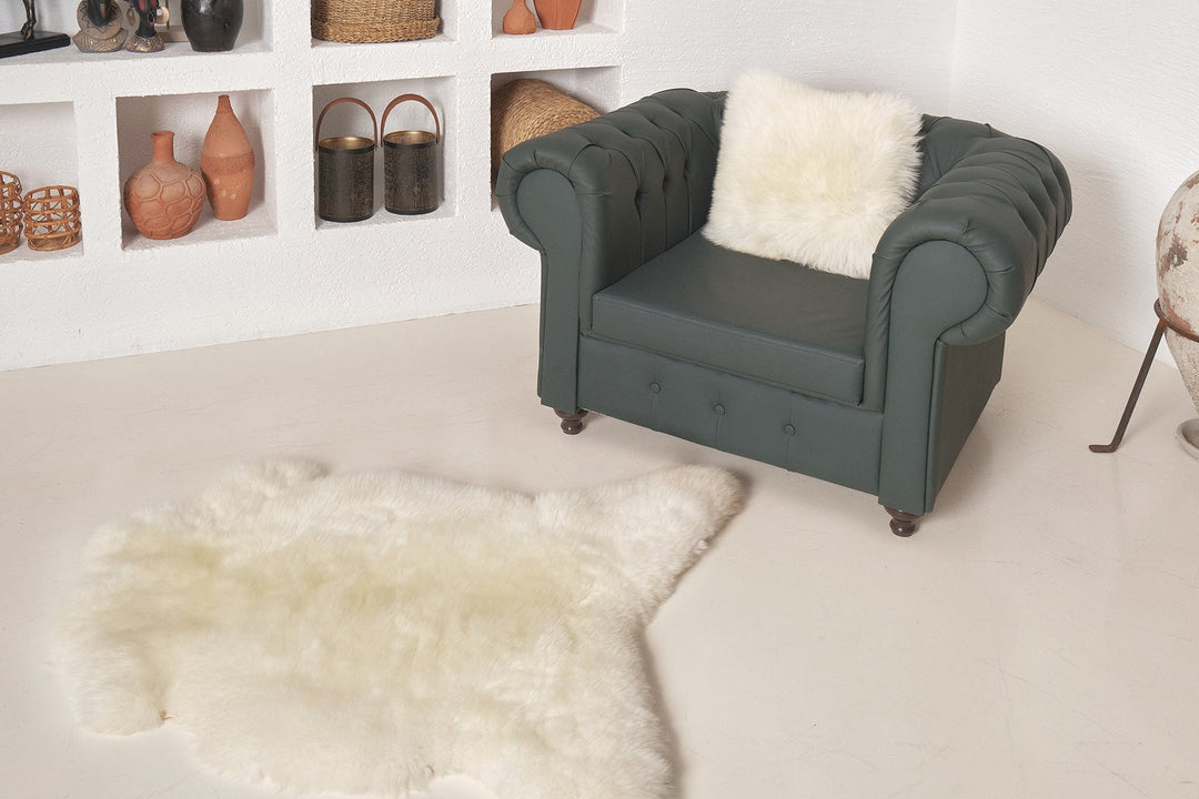 White sheepskin rug beside green armchair