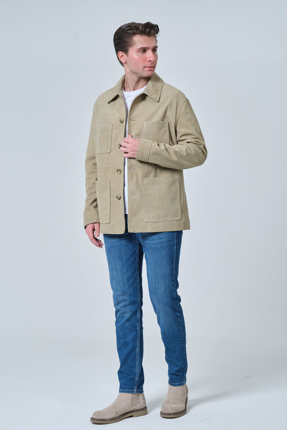 Male model wearing Beckett men's sage green suede chore jacket with blue denim jeans and beige suede boots