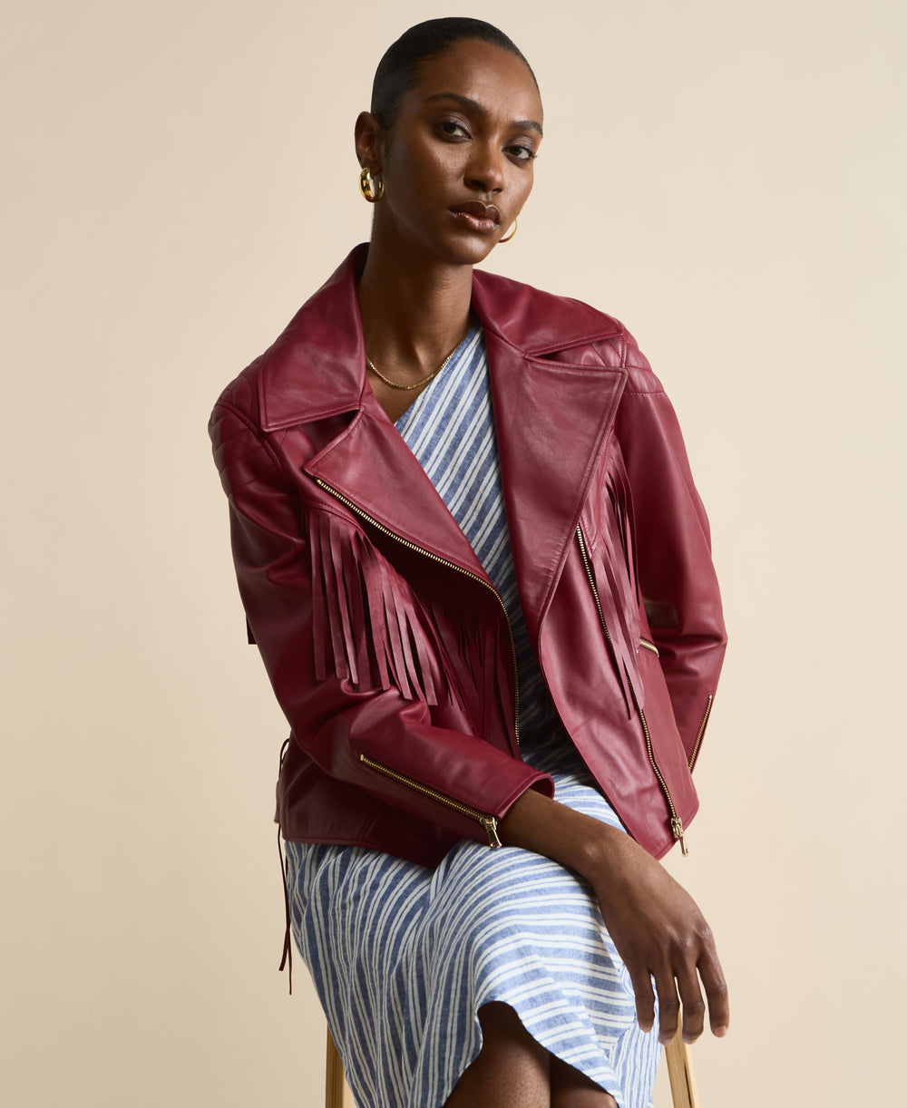 Model wearing Dakota light burgundy fringed leather jacket seated