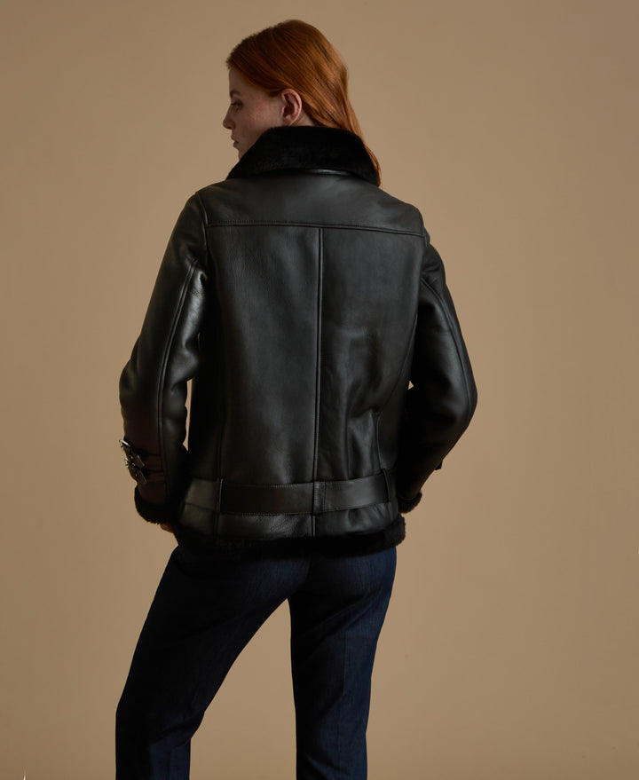 Woman wearing black shearling jacket - back view