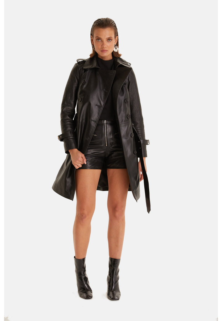 Front view of the Greenwich black leather trench coat worn open with leather shorts and ankle boots.