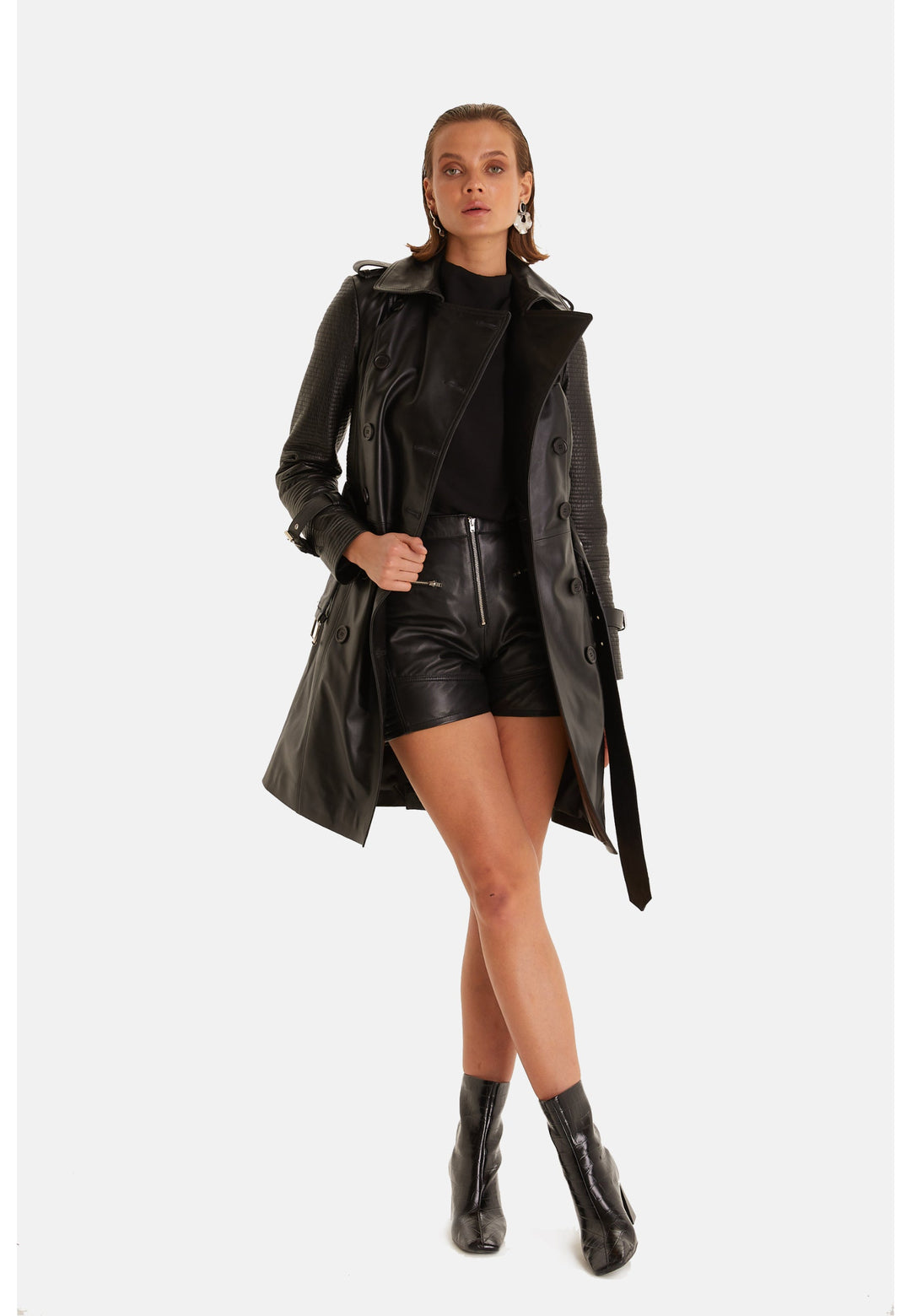 Greenwich black leather trench coat styled open over a black top and leather shorts.