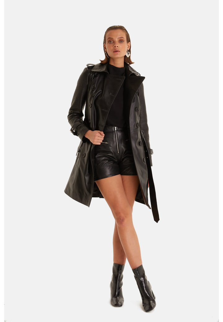 Greenwich black leather trench coat styled open over a black top and leather shorts.