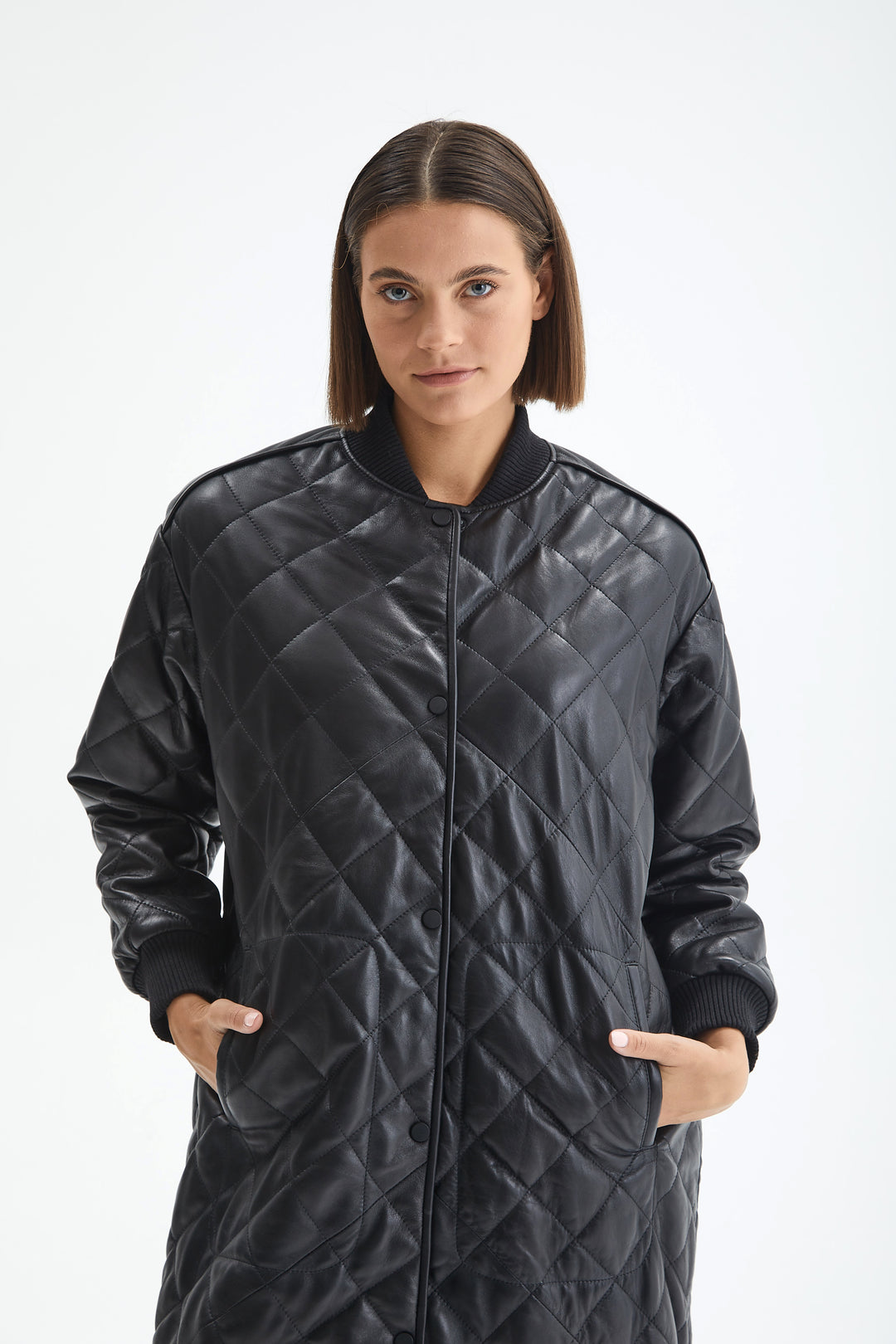 Close-up of the Kensington black leather coat showing diamond quilting, tonal snaps and ribbed cuffs.