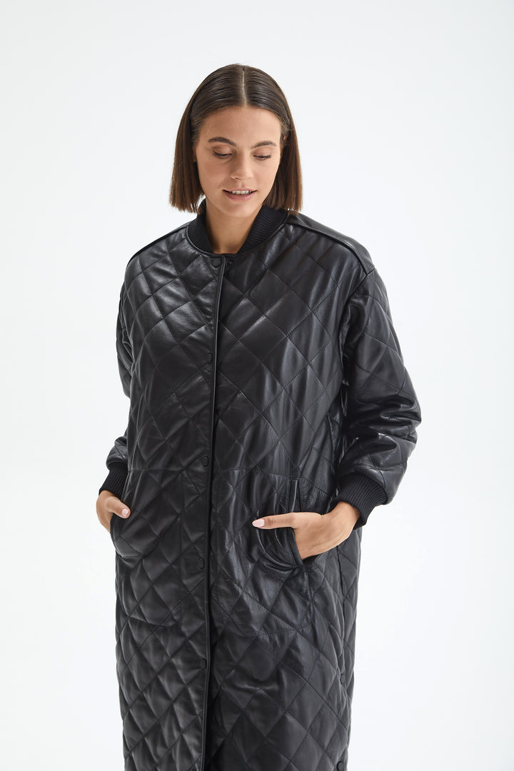 Angled detail of the Kensington black quilted leather coat showing side pockets and the ribbed collar.