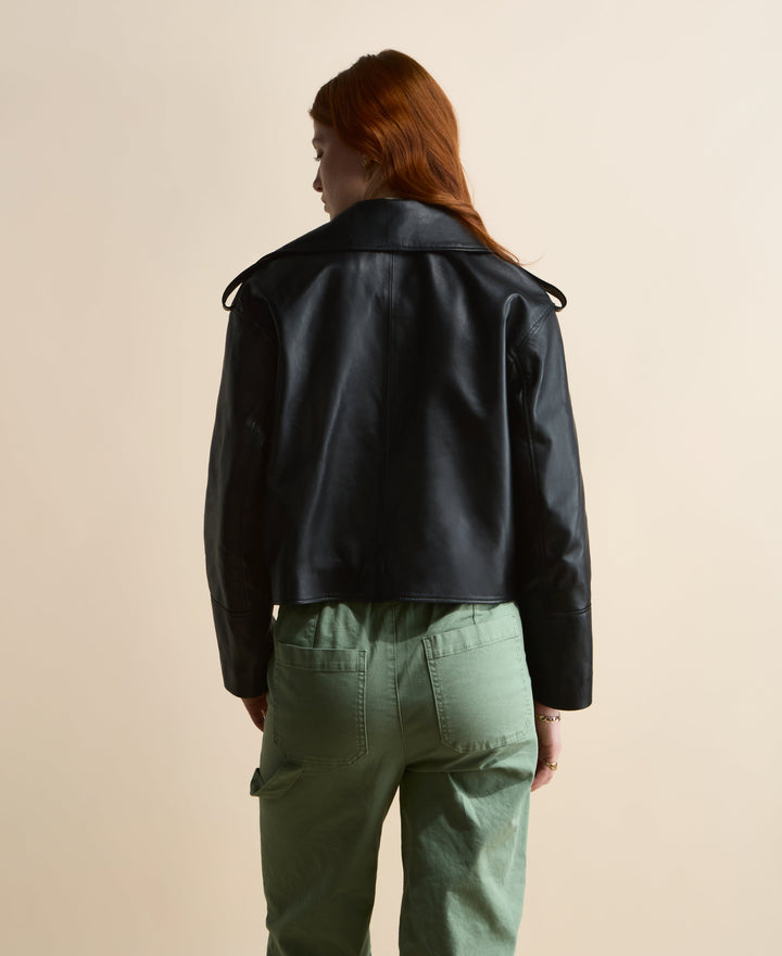 Back view of the Lola cropped black leather trench coat showing the waist-length hem and shoulder epaulettes.