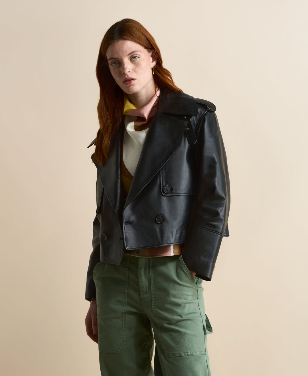 Front view of the Lola cropped black leather trench coat showing shoulder epaulettes and storm-flap detailing.