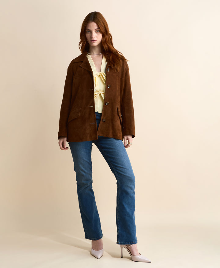 Front view of the Vera chestnut brown suede jacket worn open with a cream blouse and blue jeans.