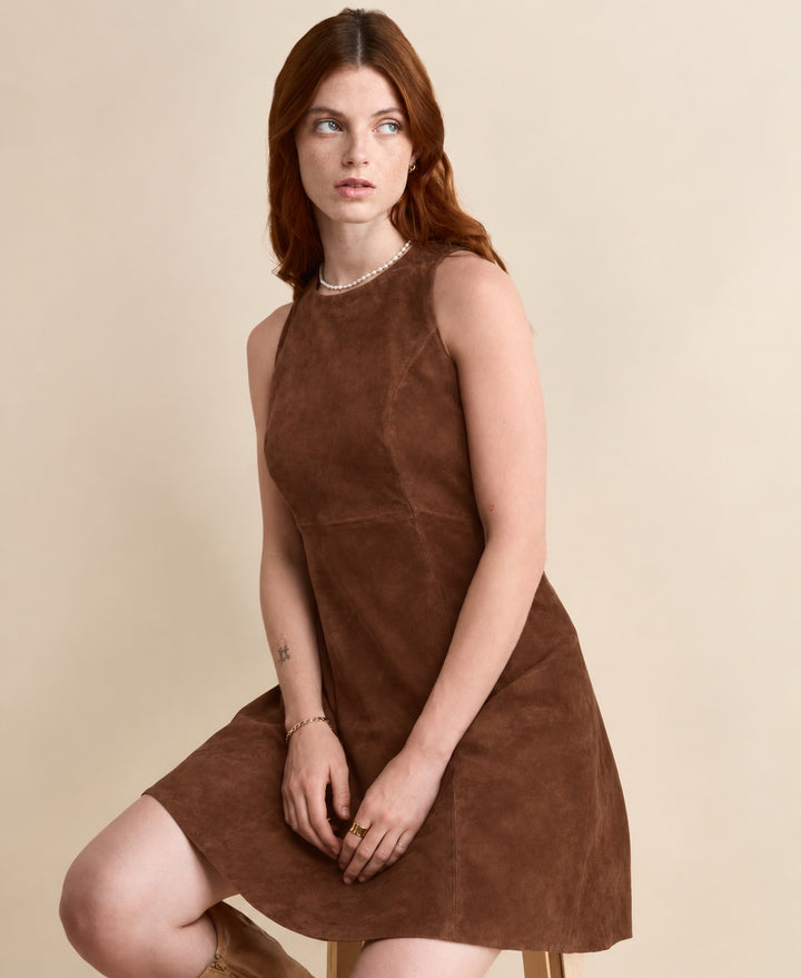 Model seated in the Helene Suede Dress in chestnut brown, showing the fitted waist and mini-length hem.

