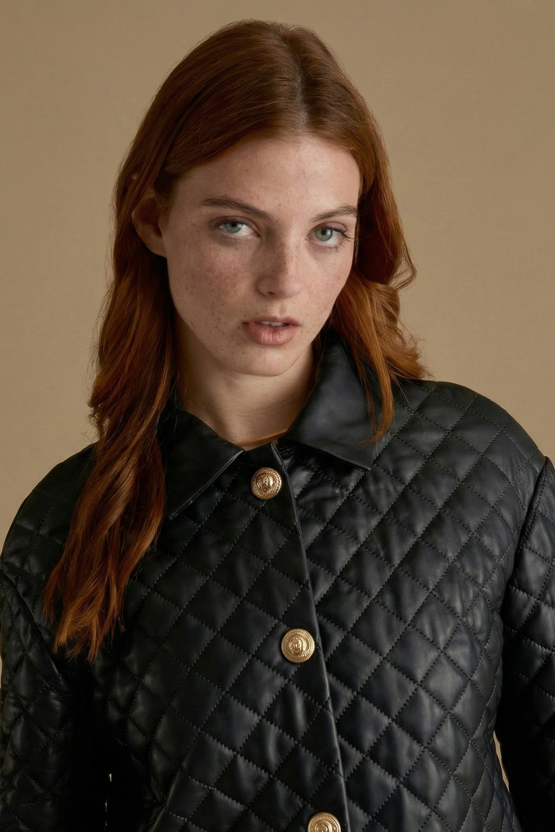 Close-up detail of Holland black quilted leather coat with diamond stitching and gold buttons