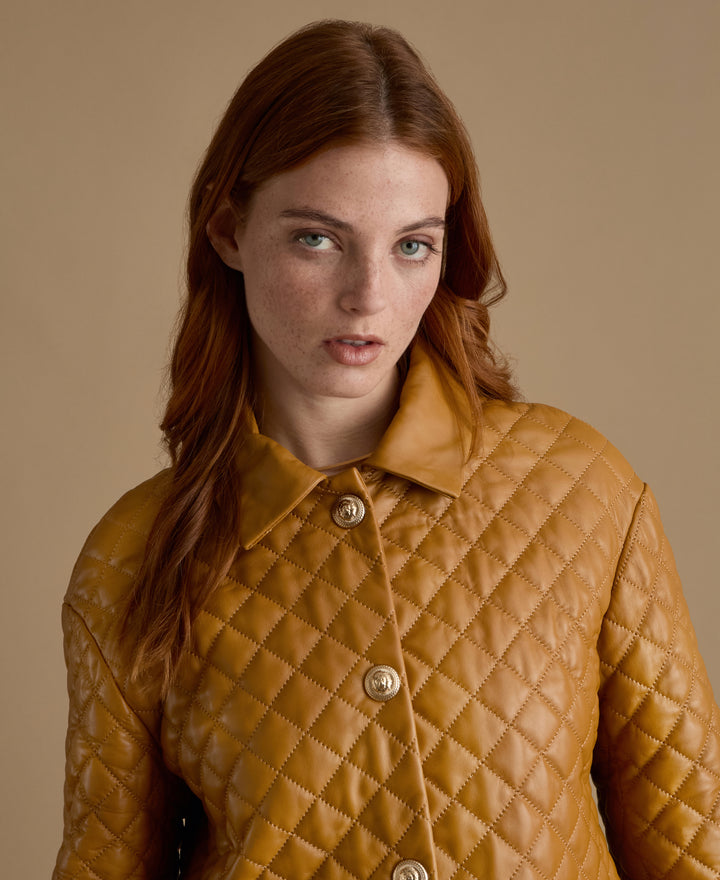 Close-up of Holland caramel quilted leather coat with diamond stitching and gold buttons