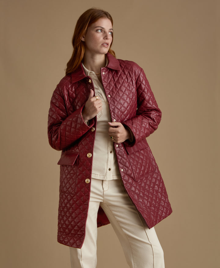Angled view of Holland light burgundy quilted leather coat with gold-tone buttons