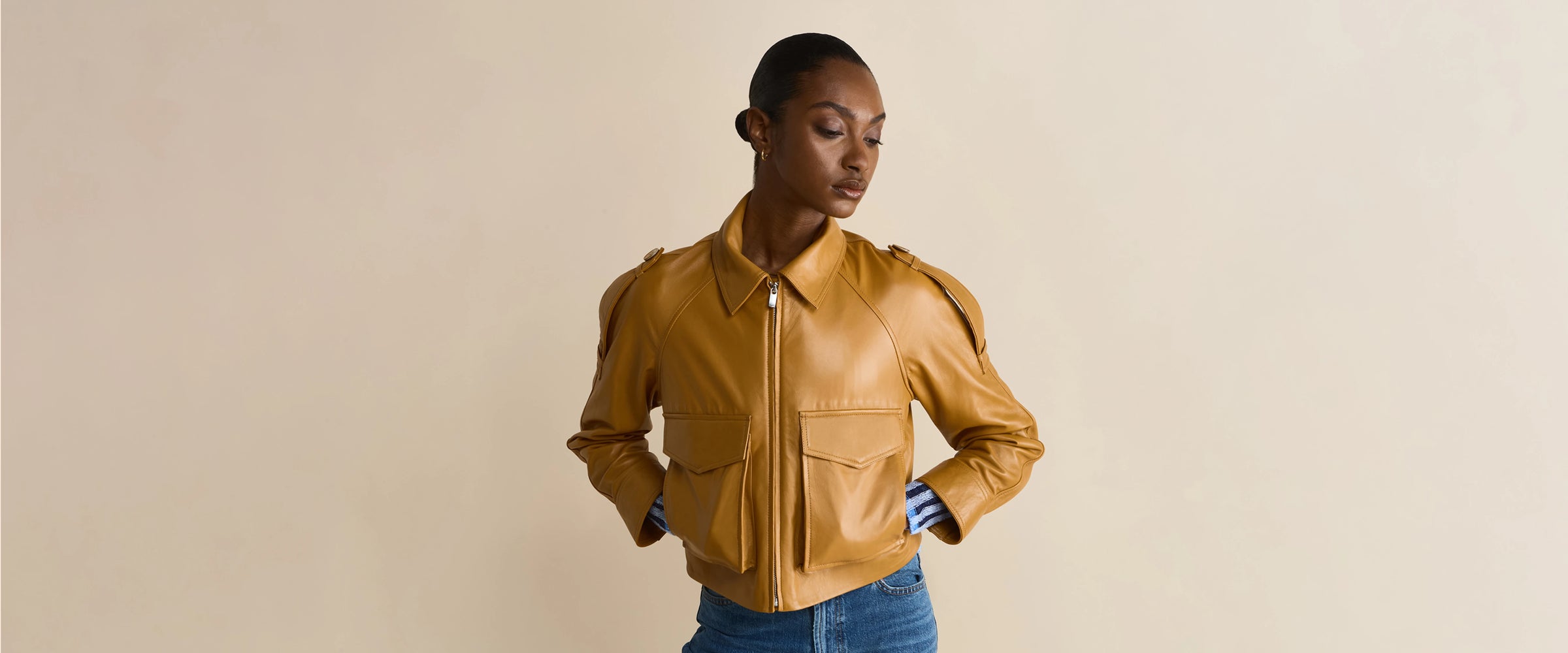 Woman wearing chestnut brown leather cropped jacket with front pockets and zip closure