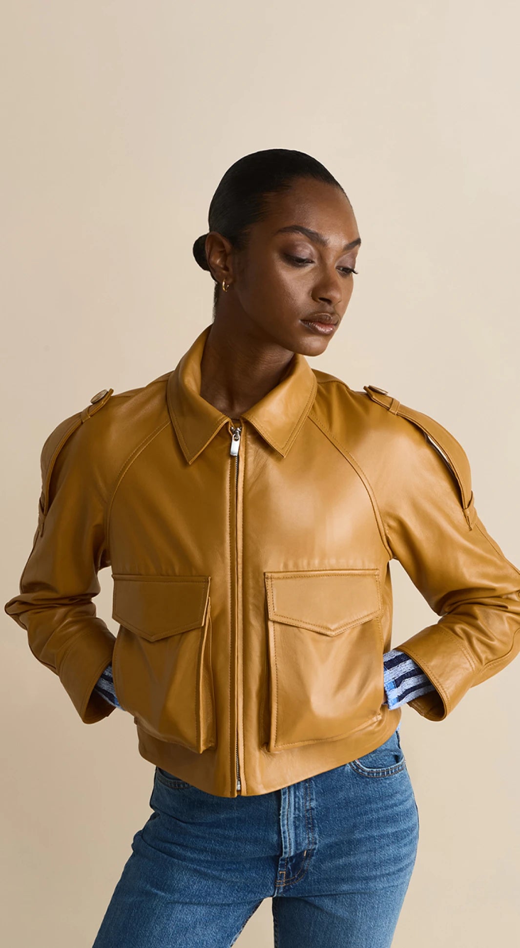 Woman wearing chestnut brown leather cropped jacket with front pockets and zip closure